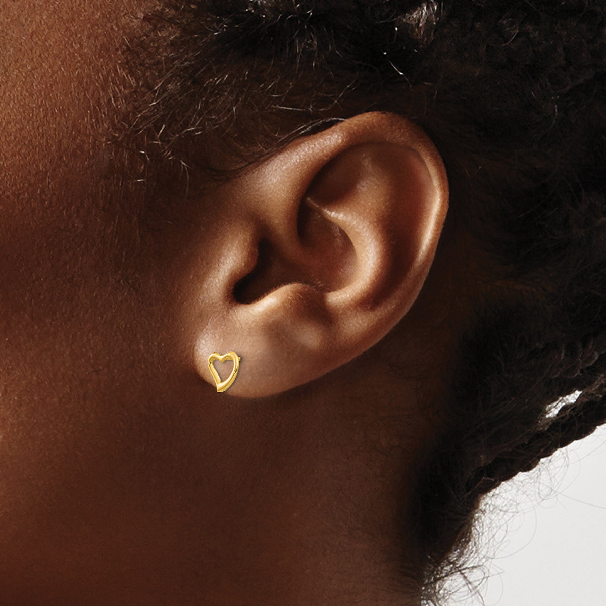 Children’s 14K yellow gold open heart stud earrings 7mm shown on ear