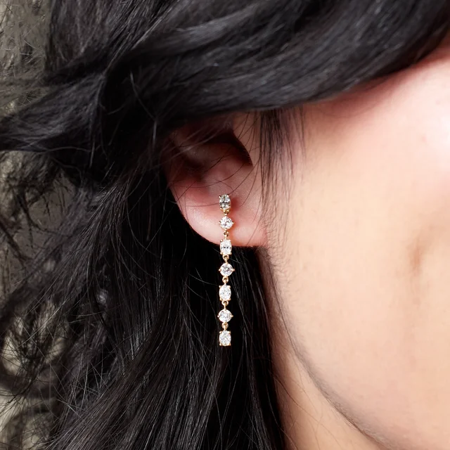 Model wearing the 14K yellow gold alternating lab-grown diamond dangle earring at its true statement length