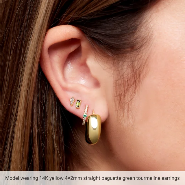 Model wearing 4 x 2 mm natural green tourmaline baguette stud earring in 14K yellow gold