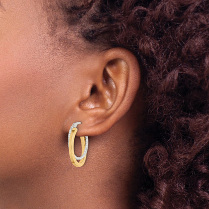 Gold-tone twisted oval hoop earrings worn on ear