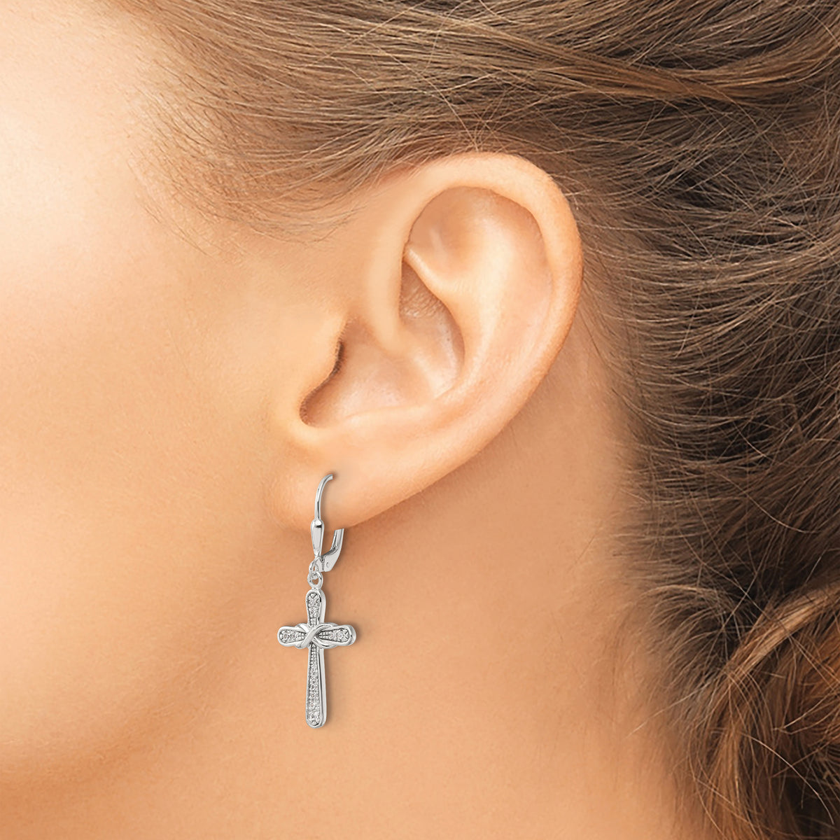 Sterling silver CZ infinity cross earrings worn on ear